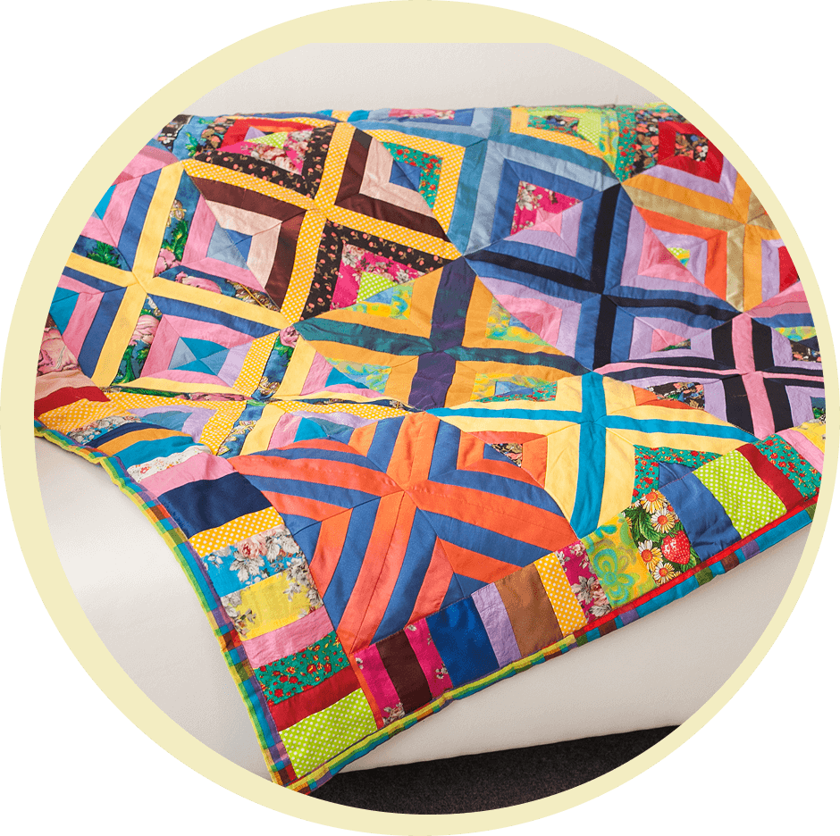 A colorful patchwork quilt with geometric patterns draped over a white sofa.
