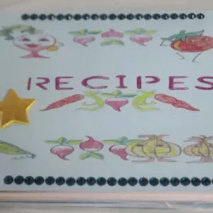 A handmade recipe book cover with "RECIPES" in bold. It features whimsical drawings of vegetables, a yellow star sticker, and decorative dots along the edges.