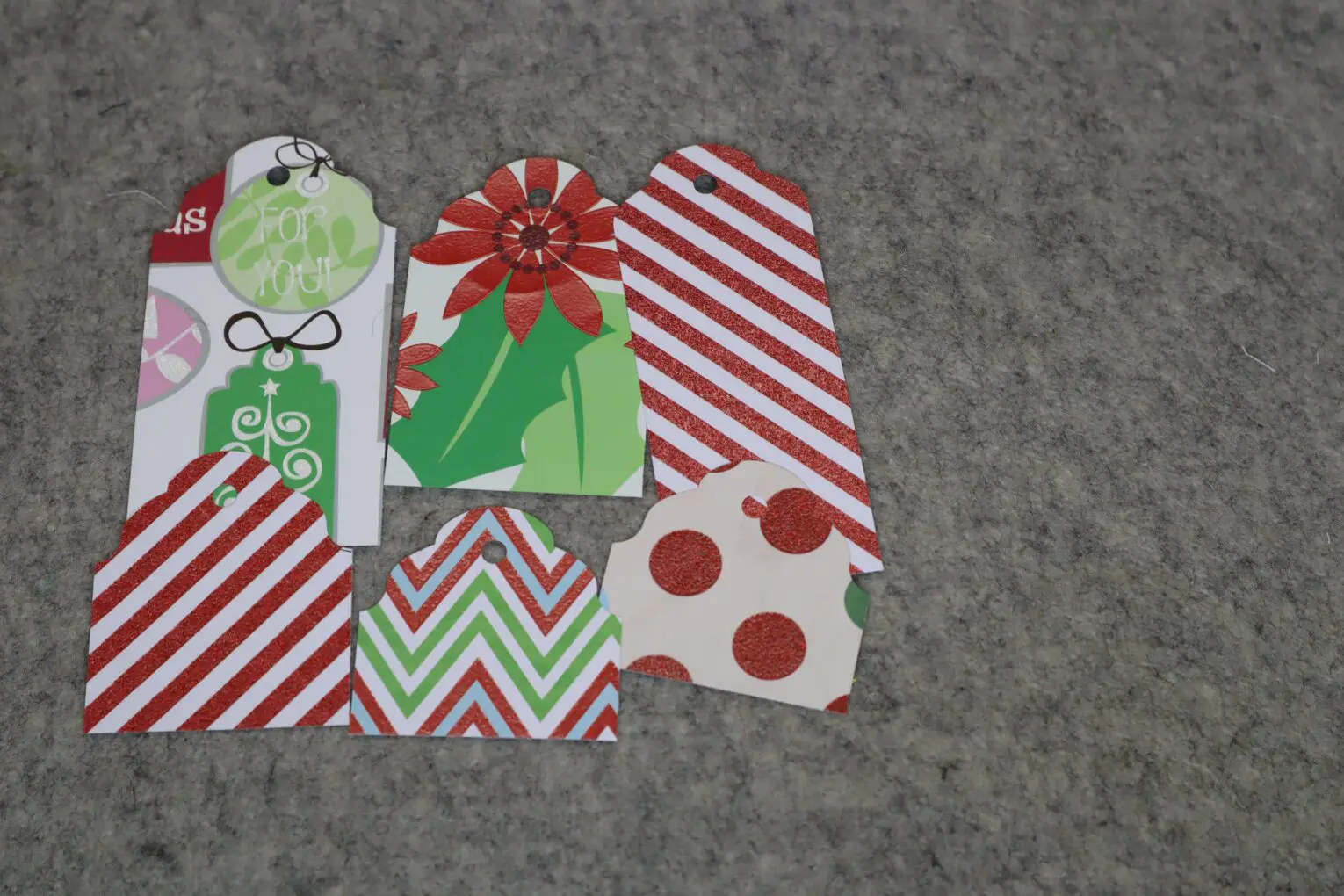 Colorful holiday gift tags arranged on fabric.