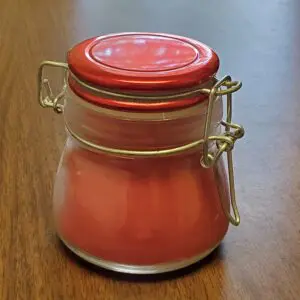 A small glass jar with pink contents and a metal clasp lid.