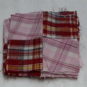 Folded fabric pieces with red and pink plaid patterns.