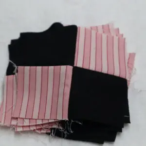 Stack of black and pink striped fabric pieces on a white surface.