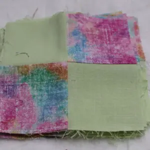 A fabric piece with four colorful patches on a green cloth.
