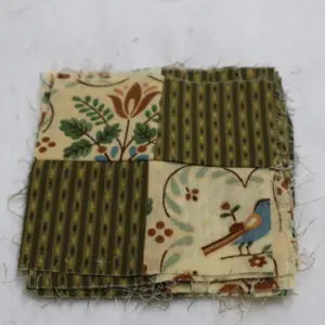 A fabric patchwork with floral and bird patterns in earthy tones.