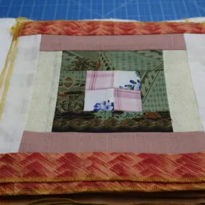 Handcrafted quilt block with a house design and colorful fabric.
