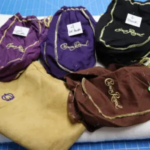 Five velvet drawstring bags in various colors with embroidered brand names.