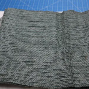 A folded piece of gray knitted fabric on a blue surface.