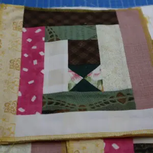A handmade quilt block with various patterned fabrics sewn together.