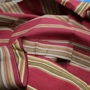 Close-up of colorful striped fabric with red, pink, yellow, and beige hues.