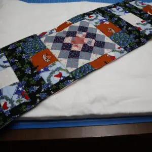A folded patchwork quilt with various patterns and colors.