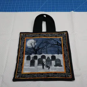 A Halloween-themed tote bag with tombstone designs and a moonlit night scene.