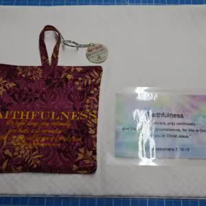 Beautifully patterned fabric pouch with a hanging loop beside a laminated ID card.