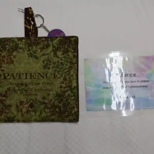 A green camouflage pouch with a keychain and a laminated card beside it.