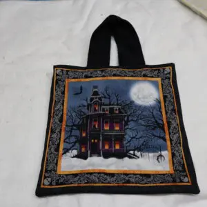 Black tote bag with a spooky haunted house design and full moon.
