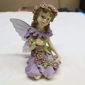 Delicate fairy figurine in a purple dress adorned with flowers.
