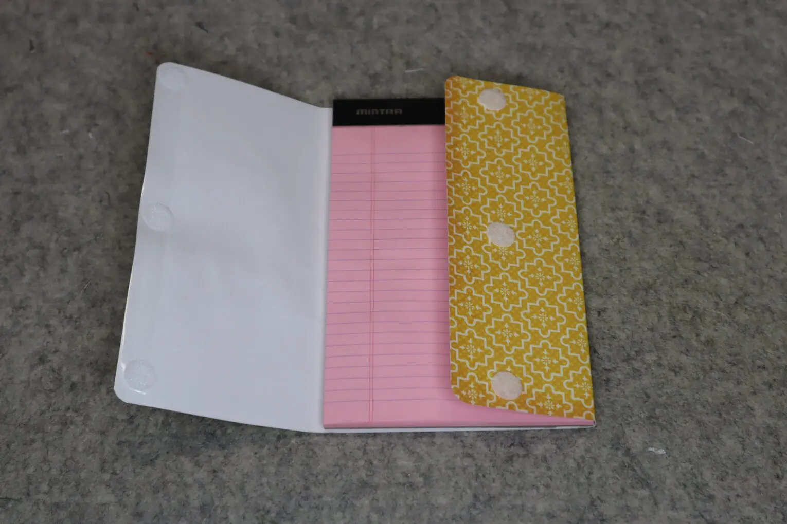 A notebook with a pink lined page and a yellow patterned cover.