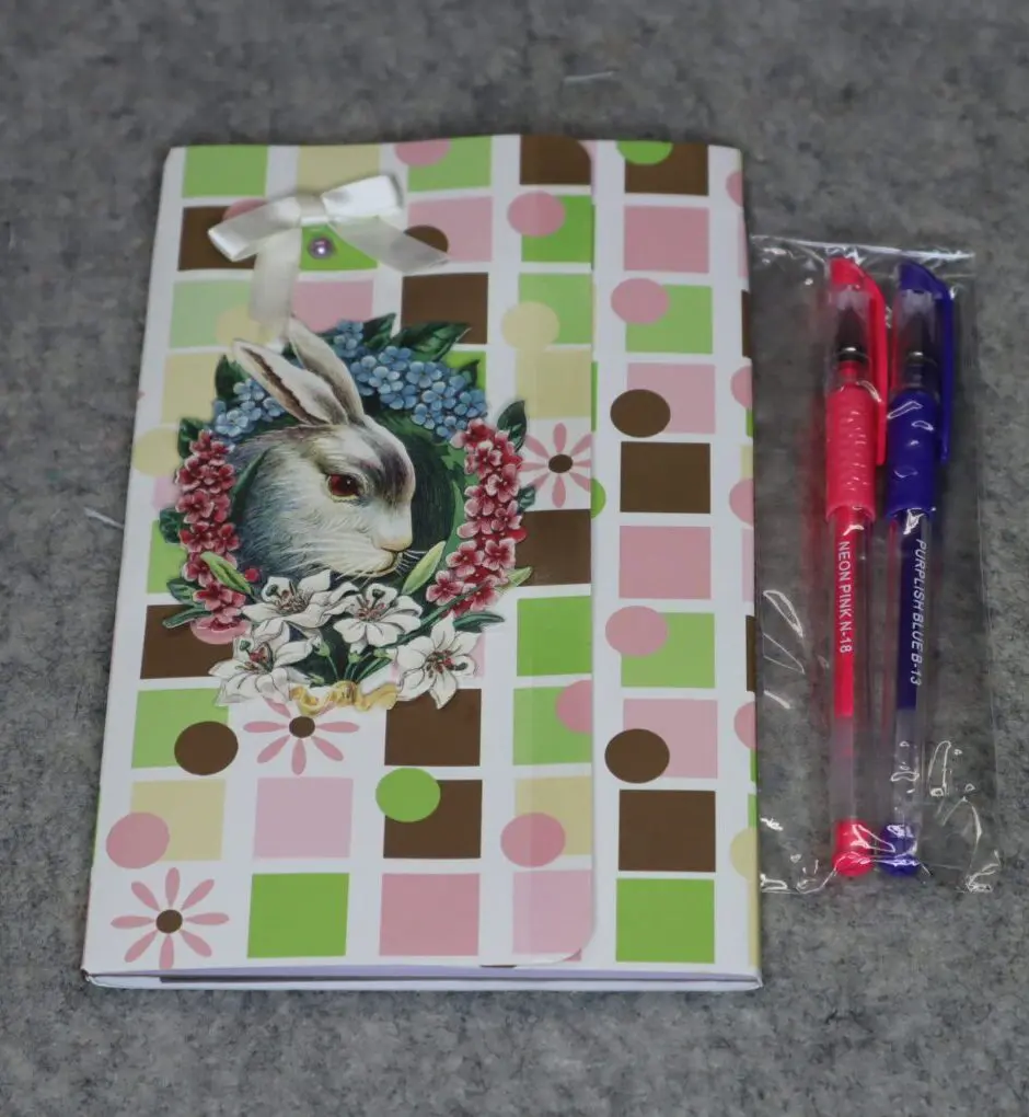 A decorated diary with a pen beside it on a gray surface.