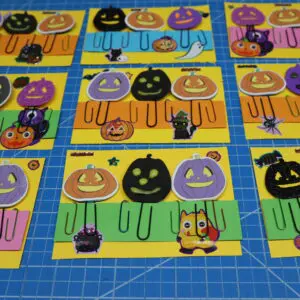 Colorful Halloween-themed cards with pumpkins and cats on a blue grid surface.