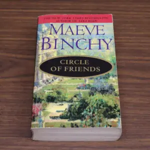 Paperback book titled 'Circle of Friends' by Maeve Binchy on a wooden table.