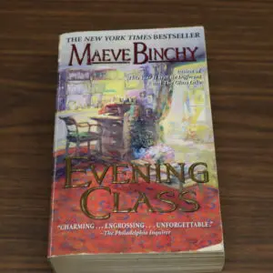 Paperback copy of 'Evening Class' by Maeve Binchy on a wooden surface.
