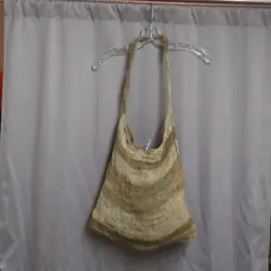 Handwoven beige and brown shoulder bag hanging on a clear hanger.