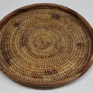Handwoven circular wicker basket with intricate patterns.