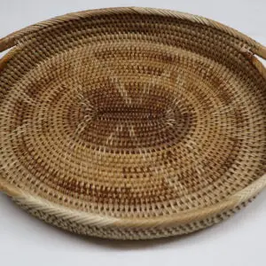 Round woven basket tray with intricate patterns and handles.