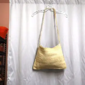 A gold textured handbag hanging on a white curtain rod.