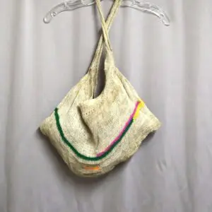 Handmade felt shoulder bag with colorful stripes on light fabric.