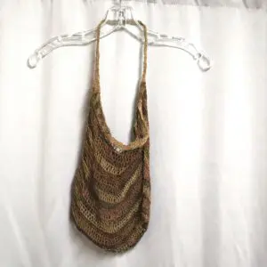 Brown woven shoulder bag hanging on a clear hanger.