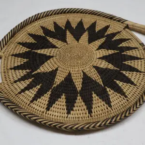 Handwoven round fan with black starburst design.