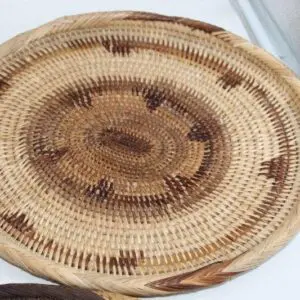 Handwoven circular basket with natural and dark patterns.