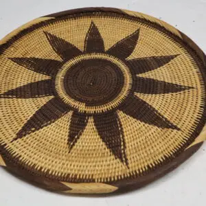 Round woven basket with a dark sunburst pattern.