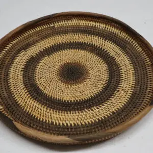 Handwoven round basket with concentric circular patterns in earthy tones.