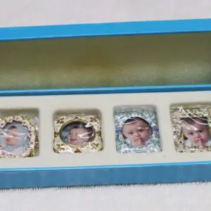 Framed four baby photos with gold decorative borders in a blue box.