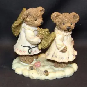 Two teddy bear figurines in white clothes standing on a cloud base.