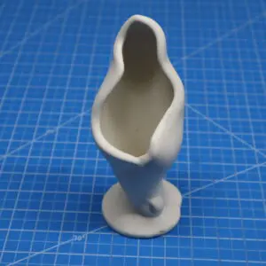 Unpainted ceramic figurine on a blue cutting mat.