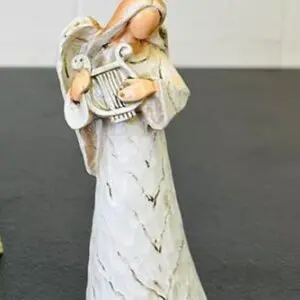 A woman in a long dress holding a baby wrapped in a blanket.
