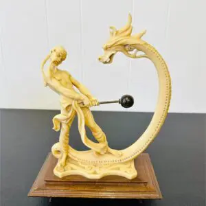 Intricate sculpture of a figure battling a dragon with a spear.
