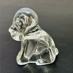 Clear glass figurine of a dog sitting on a black surface.