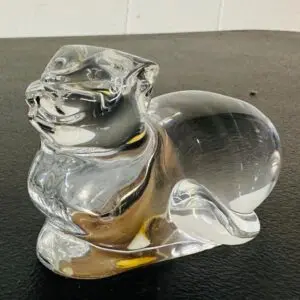 A clear glass sculpture of a reclining cat with a smooth finish.