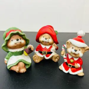 Three festive teddy bears dressed in Christmas outfits.