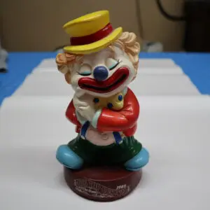 A colorful clown figurine with a yellow hat and red jacket.