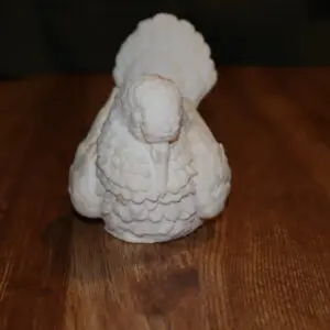 A white decorative bird sculpture on a wooden surface.
