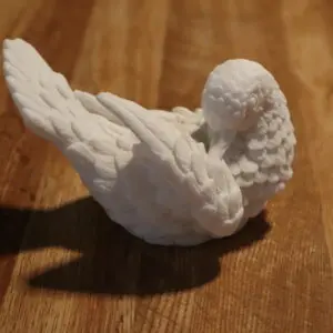 A small white ceramic bird figurine on a wooden surface.