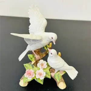 Porcelain figurines of two white doves on a floral branch.