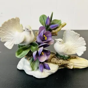 Delicate white doves with purple flowers on a decorative base.