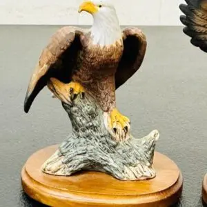A detailed bald eagle sculpture perched on a wooden base.