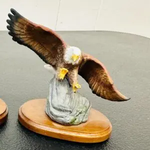 A detailed eagle sculpture with wings spread, perched on a wooden base.
