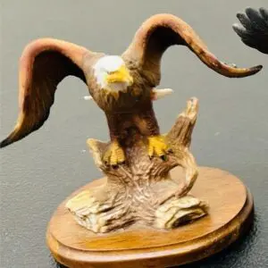 Carved eagle sculpture perched on a wooden base.